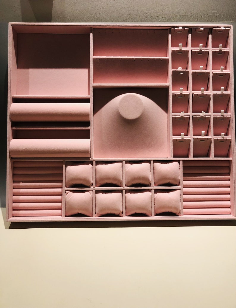 May include: A pink velvet jewelry box with compartments for rings, earrings, necklaces, and bracelets. The box has a ring roll, a watch cushion, and a necklace holder.