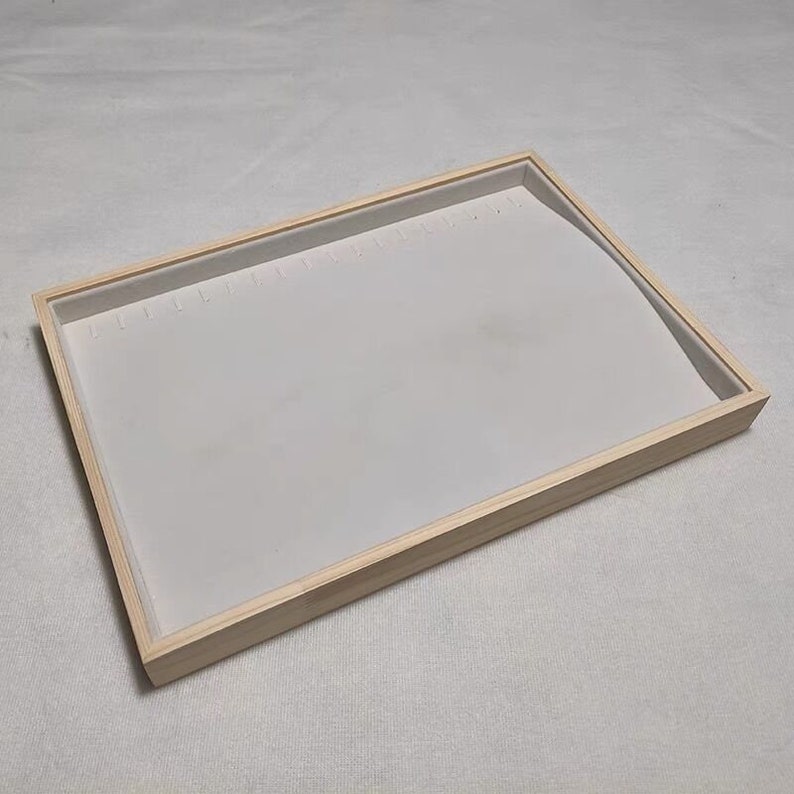 May include: A wooden jewelry tray with a white velvet lining and multiple slots for earrings.