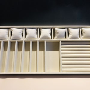 May include: A white jewelry tray with compartments for rings, bracelets, and watches. The tray has a velvet lining and a ring roll.