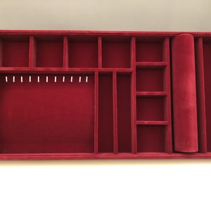 May include: Red velvet jewelry organizer with multiple compartments, including a roll for storing necklaces or bracelets.
