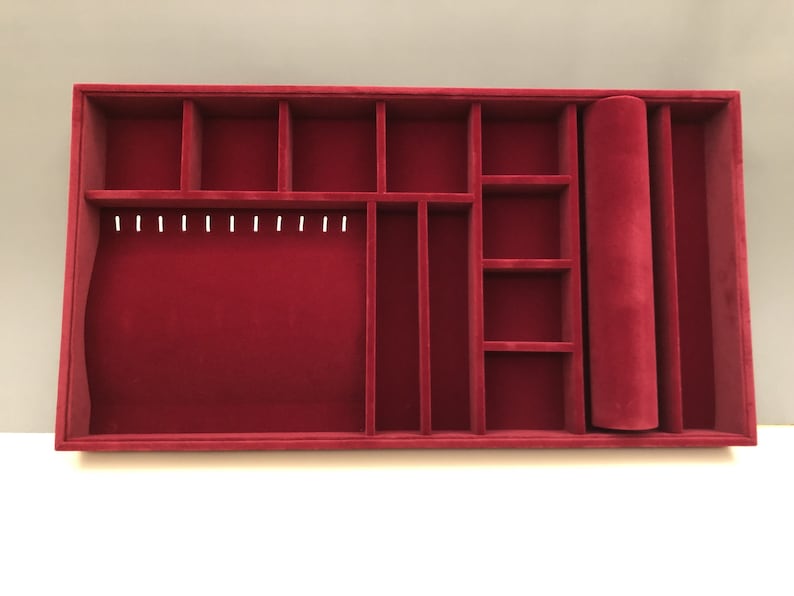 May include: Red velvet jewelry organizer with multiple compartments, including a roll for storing necklaces or bracelets.