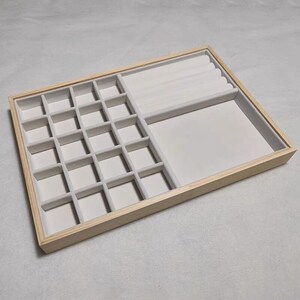 May include: A wooden jewelry box with a white velvet interior. The box has 24 small compartments and a larger section for rings.