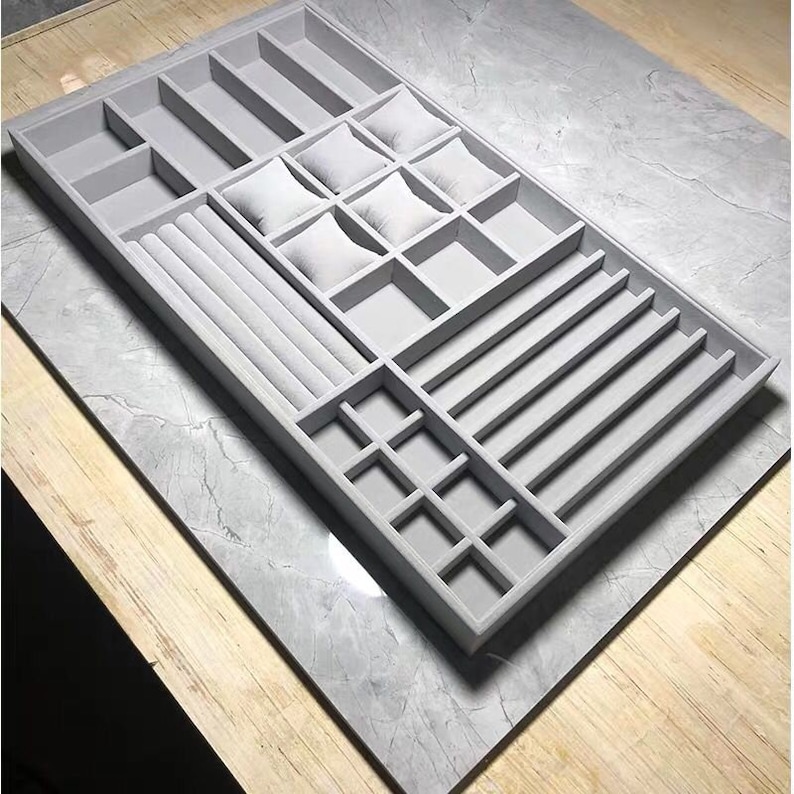 May include: A gray velvet jewelry organizer with multiple compartments for storing rings, bracelets, watches, and earrings.