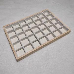 May include: A wooden jewelry storage tray with 36 compartments lined with light gray felt.