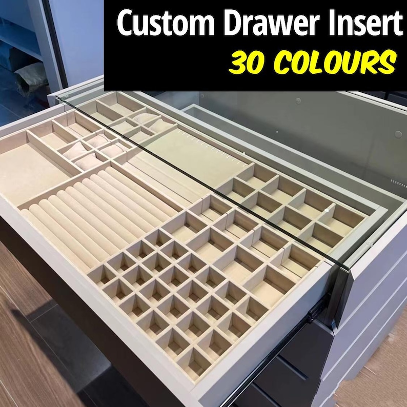 May include: A white drawer insert with a beige felt lining. The insert has compartments of various sizes for storing jewelry. The drawer is open and the insert is visible. The text "Custom Drawer Insert 30 COLOURS" is visible in the top right corner of the image.