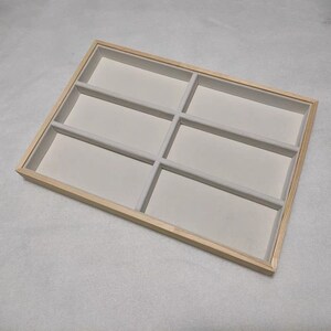 May include: A wooden tray with six compartments lined with white felt. The tray is perfect for organizing jewelry or other small items.