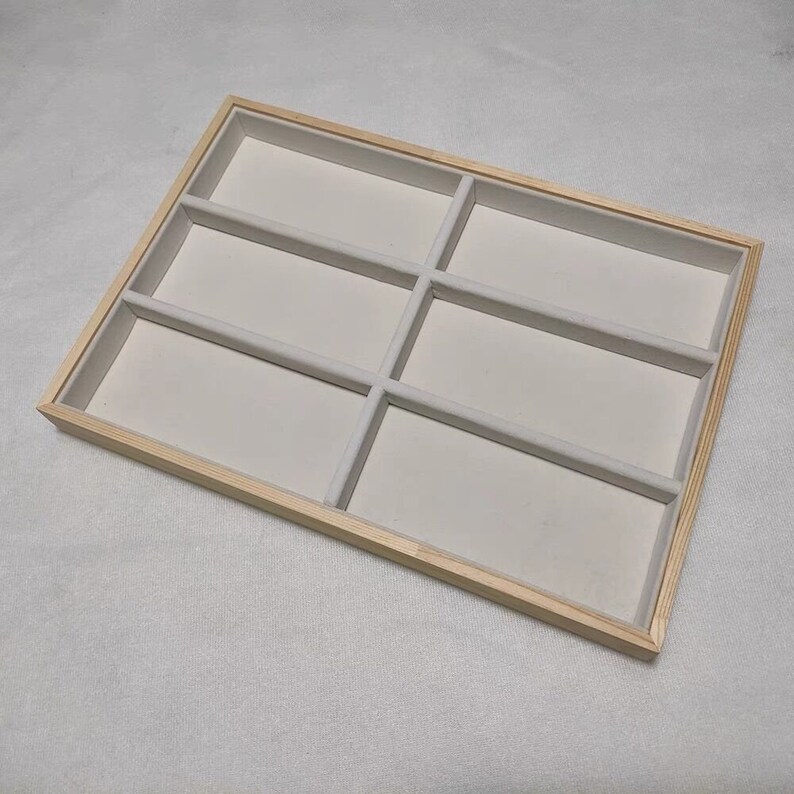 May include: A wooden tray with six compartments lined with white felt. The tray is perfect for organizing jewelry or other small items.