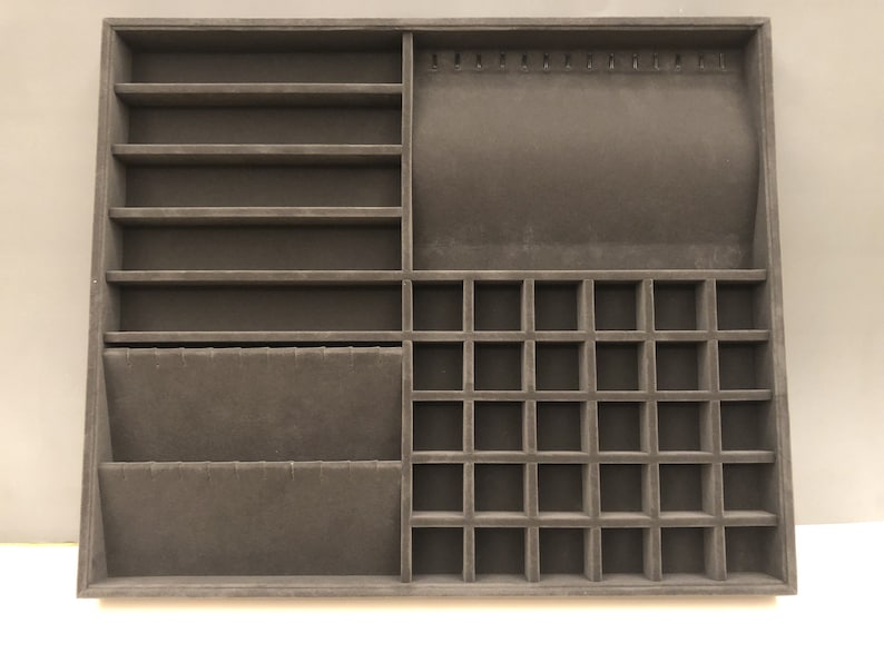 May include: A brown velvet jewelry organizer with multiple compartments for storing necklaces, earrings, rings, and bracelets. The organizer has a section with slots for hanging necklaces, a section with small squares for rings, and a section with shelves for bracelets.