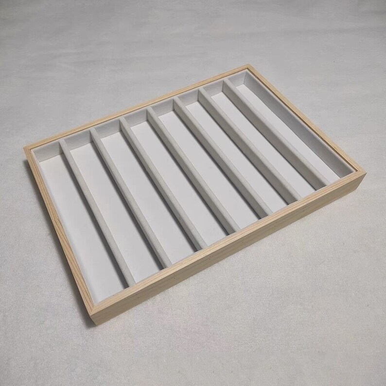 May include: A wooden tray with six compartments lined with white felt. The tray is perfect for organizing small items like jewelry or craft supplies.