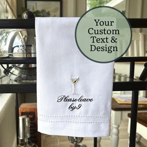 May include: A white ceramic mug with a black handle and the text "But First, Coffee" in a black, bold font. The mug is sitting on a wooden surface. The mug is approximately 4 inches tall.