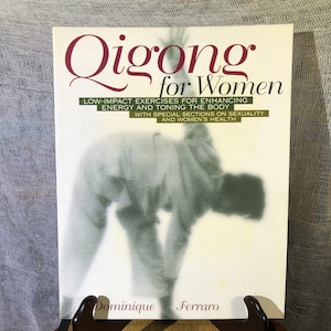 May include: A book titled "Qigong for Women" with a photo of a woman practicing qigong on the cover. The book's subtitle is "Low-Impact Exercises for Enhancing Energy and Toning the Body with Special Sections on Sexuality and Women's Health". The author's name is Dominique Ferraro.
