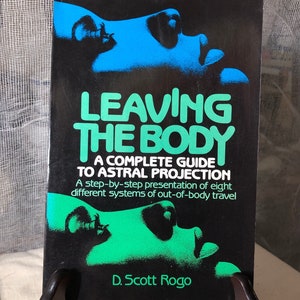 May include: A black book with a green and blue image of a face on the cover. The title is "Leaving the Body: A Complete Guide to Astral Projection". The author is D. Scott Rogo.
