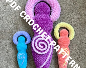 May include: Three plush, handmade figures in shades of purple, blue, and orange, each with a halo. The largest figure is purple with a pink halo and a white spiral design. The text "PDF CROCHET PATTERN" is overlaid on the image.