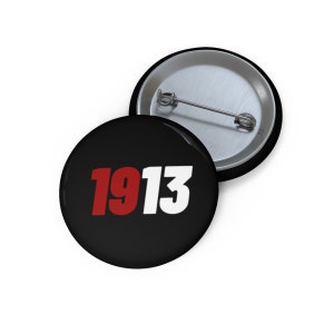 May include: A black button with a white background and the number 1913 in red and white font.