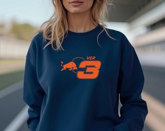 May include: A dark navy blue crewneck sweatshirt featuring a graphic on the chest. The graphic consists of an orange charging bull silhouette, the text VER, and a large orange number 3, all enclosed within a partial orange circular outline.