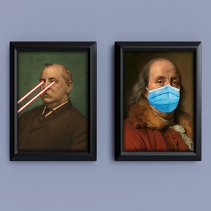 May include: Two framed portraits. One features a man with red laser beams for eyes. The other shows a man wearing a blue surgical mask. Both portraits are in black frames and set against a light blue background.