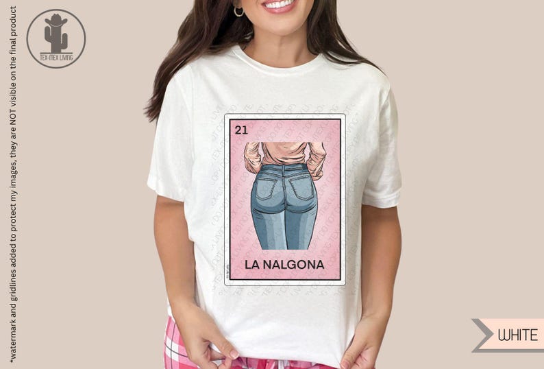 Op de afbeelding: Wit T-shirt met een roze en witte illustratie van een vrouw in blauwe jeans. De illustratie is in de stijl van een traditionele Mexicaanse speelkaart. De tekst "21" en "LA NALGONA" staat op de kaart gedrukt.
