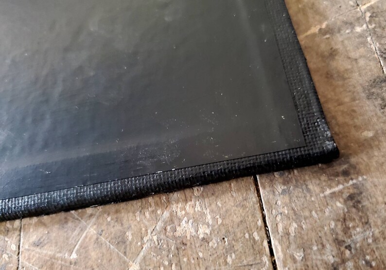 May include: Close-up of the edge of a black chalkboard with a black fabric border.