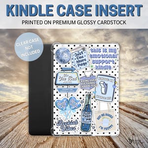 May include: A clear case insert for a Kindle e-reader with a variety of colorful stickers featuring book-themed designs. The stickers include phrases like "Just One More Page", "This is my emotional support Kindle", "The Best Hotel", "Crying Over Fictional Characters", "Sucker for Books", "Plot Twist Pop", and "Buy Me Books I'm Pretty".