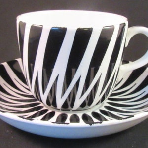 May include: A black and white striped teacup and saucer set. The cup and saucer have a bold, geometric pattern.