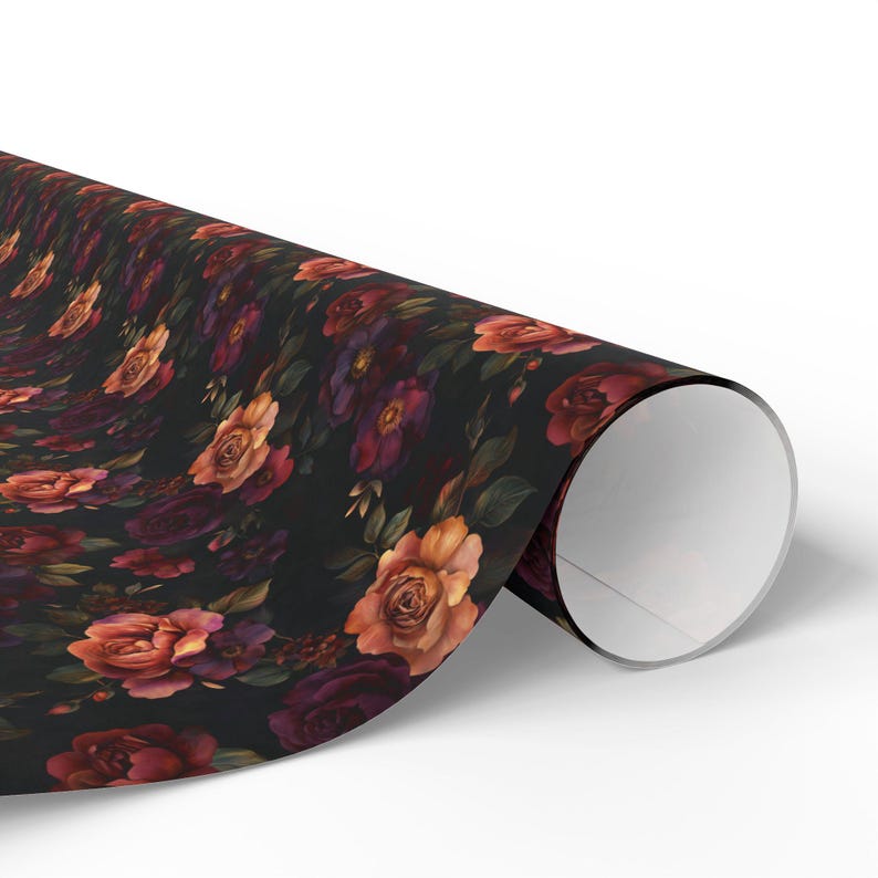 Pode incluir: Um rolo de papel de embrulho com um fundo preto escuro adornado com um padr&atilde;o denso e repetitivo de rosas em flor em tons de carmesim profundo, bord&ocirc; e laranja suave, intercaladas com folhas e folhagem verde-escura.