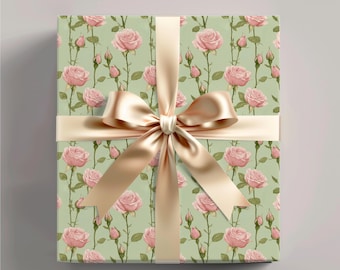Può includere: Una scatola regalo avvolta in carta verde con un motivo floreale rosa. La scatola è legata con un nastro di raso dorato.