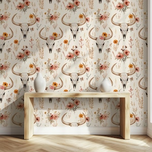 Könnte beinhalten: Eine weiße Wand mit einem sich wiederholenden Muster aus braunen Bullenschädeln und orangefarbenen, rosa und gelben Blumen. Vor der Wand steht ein Konsolentisch aus Holz mit zwei weißen Vasen.