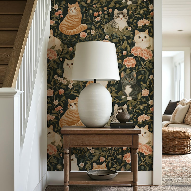 May include: A wooden side table with a white lamp and a decorative bowl. The background features wallpaper with a pattern of cats and flowers in shades of orange, white, and gray against a dark green backdrop. A staircase is visible on the left.