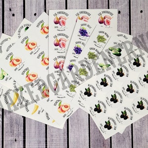 May include: A collection of white labels with various illustrations of fruits, vegetables, and berries. The labels are printed with the names of the items, such as "Peaches", "Fig Preserves", "Green Beans", and "Blackberry Jam".