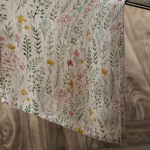 Pode incluir: Um corredor de mesa de linho bege com um padrão floral com flores e folhas de aquarela rosa, amarelo e verde.