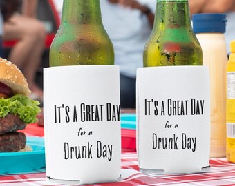 May include: Two green glass beer bottles with white koozies. The koozies have black text that reads "It's a great day for a drunk day".