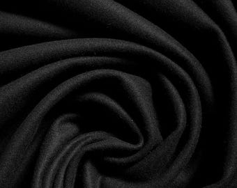 May include: Close-up of a black fabric with soft, flowing folds. The material appears to be a dense, possibly wool or fleece, with a matte finish. The dark color and texture suggest a cozy, warm textile.