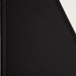May include: A roll of black fabric, partially unrolled to reveal a flat surface. The fabric is a solid, deep black color, with a slight sheen. The background is a plain white.