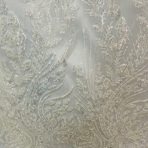 May include: White beaded fabric with a floral pattern. The beads are small and create a delicate, shimmering effect.
