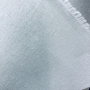 Può includere: Primo piano di un tessuto blu chiaro con una texture sottile. Il tessuto ha un bordo grezzo.