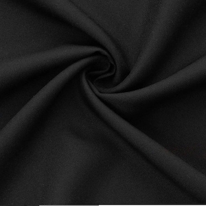 Peut inclure: Gros plan sur un tissu noir à la texture lisse et uniforme. Le tissu est plié et drapé, créant des plis et des courbes douces.