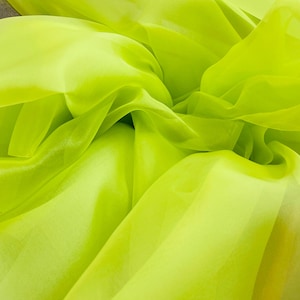 May include: A close-up of a bright green sheer fabric. The fabric is soft and flowing, with a slightly iridescent sheen.