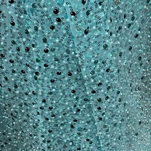 May include: Teal blue fabric with a scattered pattern of sequins and small pearls.