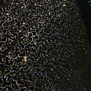 Puede incluir: Tela negra con lentejuelas iridiscentes en un patrón de remolino.