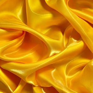 Peut inclure: Gros plan sur un tissu satiné jaune vif avec des plis fluides et un éclat brillant. La texture du tissu crée un motif dynamique de lumière et d'ombre, soulignant sa surface lisse. Idéal pour l'habillement, la décoration intérieure ou les projets d'artisanat.