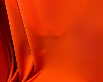 Könnte beinhalten: Nahaufnahme eines leuchtend orangefarbenen Stoffes mit sanften Falten und subtilen Schatten. Das Material wirkt glatt und möglicherweise seidig, mit einer satten, gesättigten Farbe. Der Stoff wird wahrscheinlich für Kleidung oder Heimdekoration verwendet.