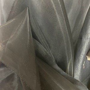May include: Black sheer fabric with a fine mesh texture. The fabric is folded and layered, creating a soft, draping effect.