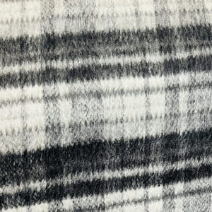 May include: Black and white striped fabric with a fuzzy texture. The fabric has a woven plaid pattern.