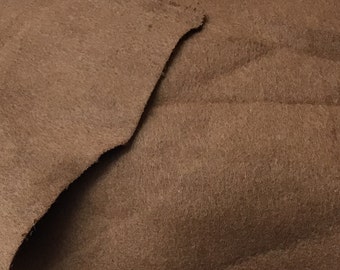 May include: Close-up of a brown suede fabric with a soft, textured surface.
