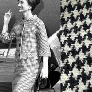 May include: A black and white houndstooth patterned fabric. The fabric has a woven texture.