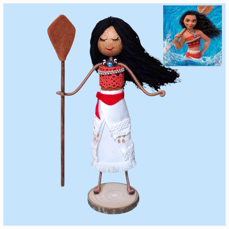 Pu&ograve; includere: Bambola fatta a mano di Moana del film d'animazione Disney Moana, con lunghi capelli neri, un top rosso, una gonna bianca e una pagaia di legno marrone.