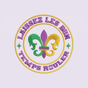 May include: Embroidered circular design with the text "Laissez Les Bon Temps Rouler" in purple. The design features a fleur-de-lis in green, purple, and gold, with gold stars and a gold border. The design is likely for Mardi Gras.