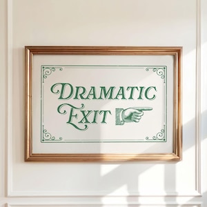 Puede incluir: Un letrero enmarcado con las palabras "Dramatic Exit" en verde. El letrero tiene un marco dorado y está montado en una pared blanca. La imagen incluye un gráfico de una mano que señala.