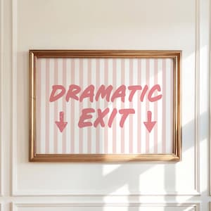 Puede incluir: Un cartel enmarcado con las palabras "DRAMATIC EXIT" en rosa, con flechas que apuntan hacia abajo. El fondo tiene rayas verticales rosas y blancas. El marco es dorado y cuelga de una pared blanca.
