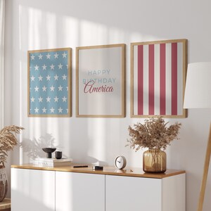 Pode incluir: Tr&ecirc;s impress&otilde;es emolduradas com um tema patri&oacute;tico. A impress&atilde;o da esquerda apresenta um fundo azul com estrelas brancas. A impress&atilde;o do centro tem o texto "Happy Birthday America" em azul e vermelho. A impress&atilde;o da direita apresenta listras vermelhas e brancas.